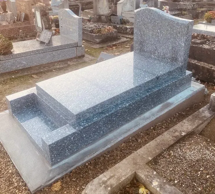 Tombe funéraire en granit bleu poli avec stèle arrondie récemment posée.