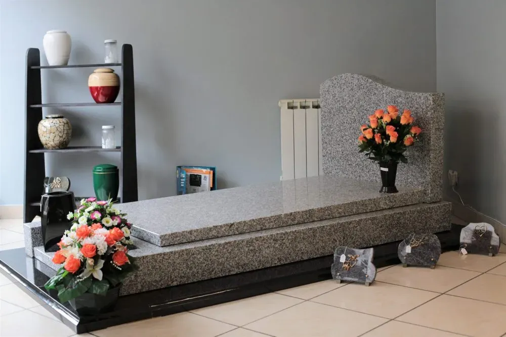Exposition d'un monument funéraire en granit et d'urnes en magasin.
